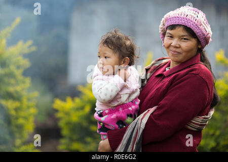 MAE KLANG LUANG, Thaïlande, le 31 décembre 2014 : Une tribu Karen femme en vêtements traditionnels est tenant son enfant dans le village de Mae Klang Luang Banque D'Images