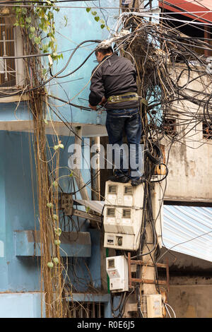 HANOI, Vietnam, 16 décembre 2014 : Un technicien debout sur les compteurs d'électricité est la réparation ou vérification de l'installation électrique en désordre dans la ville réseau Banque D'Images