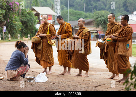 PHANG MAPHA, THAÏLANDE, 19 novembre 2012 : les femmes donnant à l'alimentation quotidienne des moines bouddhistes traditionnels au petit matin l'aumône dans le village de Phang Banque D'Images