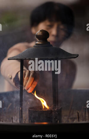 NARA, Japon, le 18 novembre 2011 : une femme japonaise est d'allumer un bâton d'encens avant de prier au Temple Todai-ji à Nara, près de Kyoto. Peu de profondeur Banque D'Images