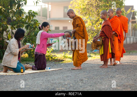 VANG VIENG, Laos, le 19 mars 2011 : les femmes donnant à l'alimentation quotidienne des moines bouddhistes traditionnels au petit matin l'aumône dans le village de Viang Vieng, L Banque D'Images