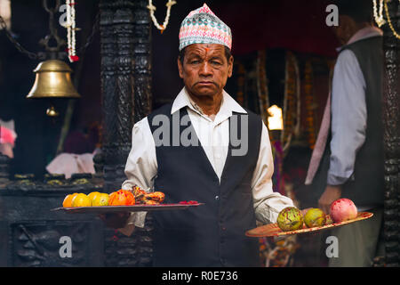 BHAKTAPUR, NÉPAL, 24 novembre 2010 : Rituel du sacrifice de chèvre : un homme à sa possession a maintenant des assiettes de fruits couverte de sang de l'animal en Bhak Banque D'Images