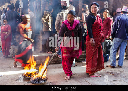 BHAKTAPUR, NÉPAL, 24 novembre 2010 : Les femmes sont inflammation bâtons longs dans la rue pour un rituel religieux hindou dans Bhaktapur, Népal Banque D'Images