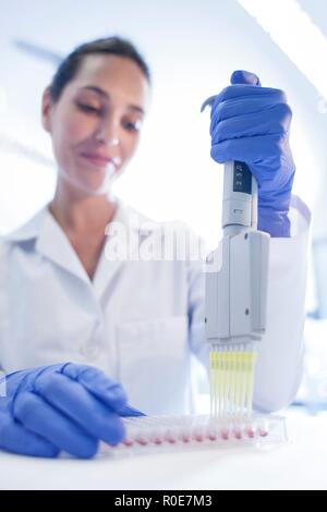 Laboratoire femelle assistant à l'aide d'une pipette multi. Banque D'Images