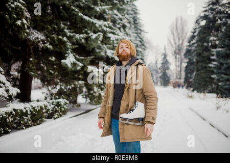 Thème Sports d'hiver. Portrait. Beau jeune homme de race blanche avec de longs cheveux et barbe rouge. En hiver pose modèle snow park contre l'arrière-plan de la fo Banque D'Images