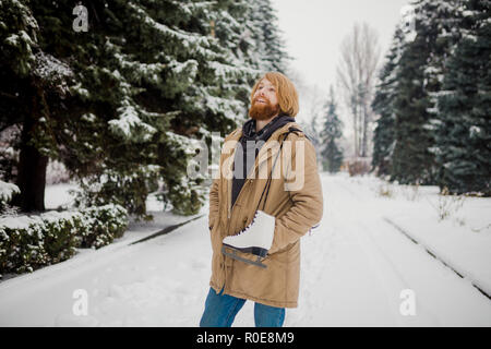 Thème Sports d'hiver. Portrait. Beau jeune homme de race blanche avec de longs cheveux et barbe rouge. En hiver pose modèle snow park contre l'arrière-plan de la fo Banque D'Images