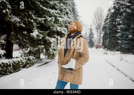 Thème Sports d'hiver. Portrait. Beau jeune homme de race blanche avec de longs cheveux et barbe rouge. En hiver pose modèle snow park contre l'arrière-plan de la fo Banque D'Images