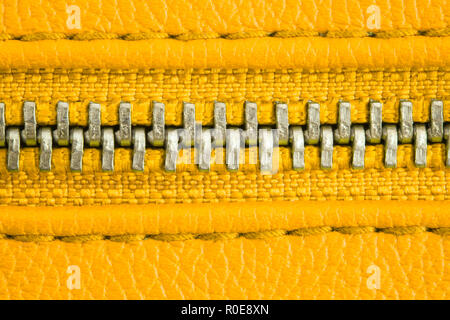 Fermeture éclair bien fermé enserrant deux couches de tissu jaune et textile cuir jaune sous un fort grossissement fermer détail la photographie comme saf Banque D'Images