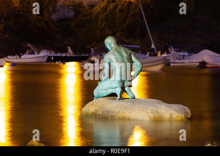 Une vue étonnante de la 'Baie du Silence', Baia del Slienzio, Sestri Levante (Ge), Ligurie, Italie, au crépuscule, avec le pêcheur de bronze sculpture Banque D'Images