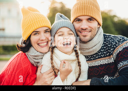 Drôle de joie petit enfant rire comme a wonderful time avec ses parents. Les parents affectueux se tiennent près de leur petite fille qui a la bonne humeur après Banque D'Images