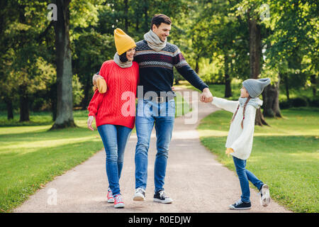 Portrait plein air de famille affectueuse walk in park, porter des vêtements en tricot chaud. Beau jeune homme tient la main de sa fille, l'air avec l'expression heureuse Banque D'Images