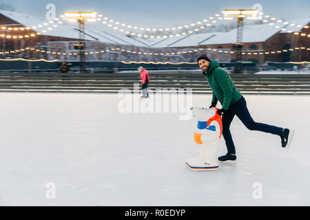 Portrait of happy senior homme skater se dresse sur l'anneau de glace, dispose d''époque, a une vie active, d'être sur la patinoire. L'homme joyeux sourire se réjouit Banque D'Images
