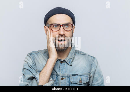 Portrait d'homme barbu ressemble étonnement excités avec surprisment à huis clos, reçoit des nouvelles inattendues, vêtu de vêtements à la mode, a lo attrayant Banque D'Images