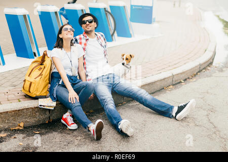 Séjour jeunes hommes et femmes d'affaires et leur garde d'animaux sur la chaussée, tout en profitant d'avoir des expressions gaies beau temps, être épuisé un Banque D'Images