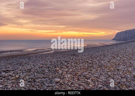 Une vue sur le rivage de Llandudno à l'aube avec un ciel rouge sur la mer. Le Little Orme est dans la distance. Banque D'Images