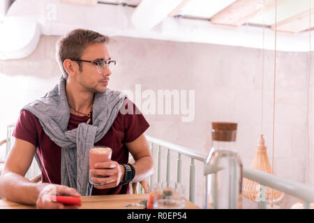 Homme barbu élégant portant smart watch holding glass of fruits Banque D'Images