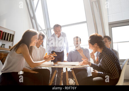 Cheerful équipe diversifiée des gens rire au blague toget eating pizza Banque D'Images