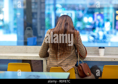 Jeune femme assise seule dans un café Banque D'Images