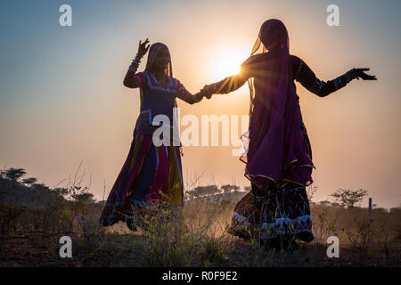 Deux silhouettes de femmes gitanes dancing au coucher du soleil, Pushkar Camel Fair, Pushkar, Rajasthan, India Banque D'Images