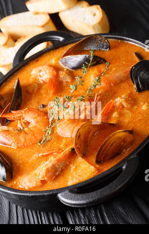 Suquet de Peix soupe aux fruits de mer, pommes de terre, les herbes et le poisson assaisonné avec picada close-up dans une casserole sur la table verticale. Banque D'Images