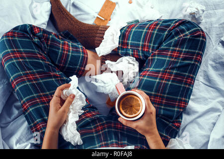 Vue de dessus sur la femme malade au lit tenant une tasse de thé à l'orange en c Banque D'Images