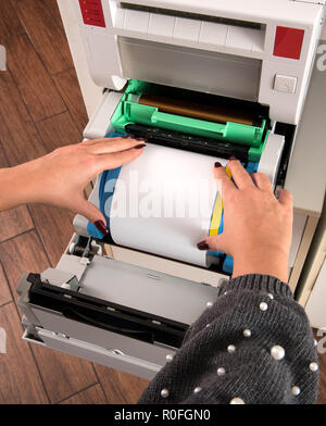 Femme loading un nouveau rouleau de film photographique du papier dans une imprimante dans un gros plan de haut en bas vue de ses mains Banque D'Images