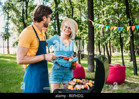 Cheerful couple having barbecue en été park Banque D'Images