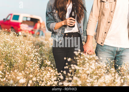 Cropped shot of couple holding hands and walking par champ de fleur Banque D'Images