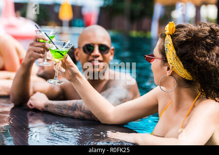 Jeune couple clinking glasses de cocktails près de la piscine Banque D'Images