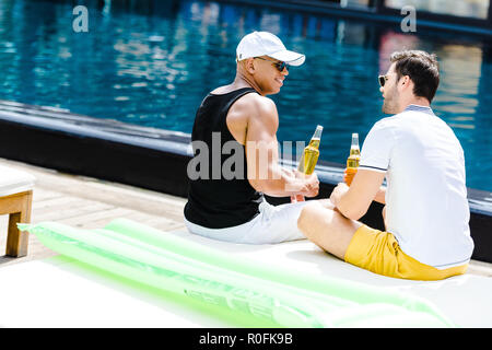 Male amis assis avec un café proche piscine Banque D'Images