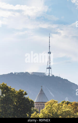 Vue de la tour de télévision sur la montagne Mtatsminda et église à Tbilissi, Géorgie. Les arbres au premier plan. Banque D'Images