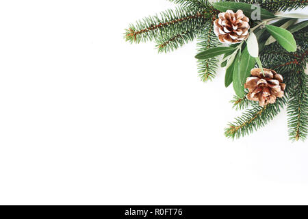 Fête de Noël le titre de la composition du stock. Coin décoratif. Cônes de pin, sapin et olivier feuilles et branches en bois blanc arrière-plan. Mise à plat, vue du dessus. Copier l'espace. Banque D'Images