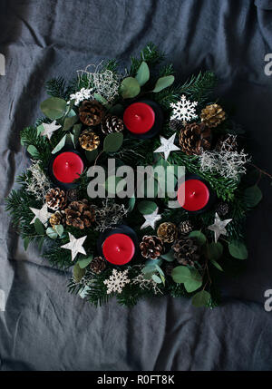 Composition de la guirlande de noël sur fond gris foncé linge de table. Faites de branches de sapins d'evergreen, de feuilles d'eucalyptus, des flocons de neige, d'or et de pommes de pin naturel. Mise à plat, vue du dessus. Banque D'Images