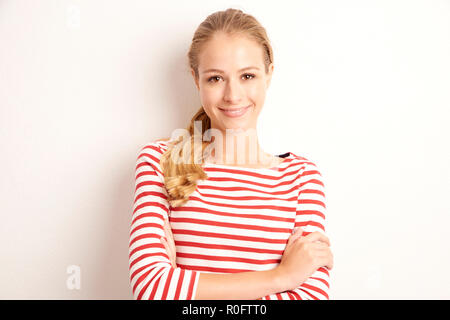 Portrait de la belle jeune femme portant chemise rayée tout en regardant la caméra et debout à l'arrière-plan blanc isolé. Banque D'Images