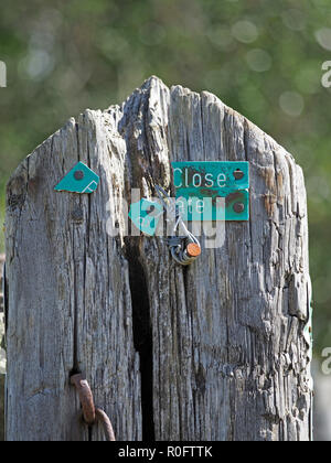 Weathered barrière et usé de Cumbria, Angleterre, RU avec du mauvais signe en plastique bleu qui devrait dire "fermez la porte" Banque D'Images