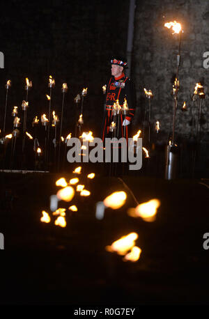 Yeoman Warders ('Beefeaterss') éclairant la première des milliers de flammes dans une cérémonie d'éclairage dans la lande sèche de la Tour de Londres dans le cadre d'une installation appelée au-delà de l'ombre profonde: La Tour se souvient, pour marquer le centenaire de la fin de la première Guerre mondiale. Banque D'Images