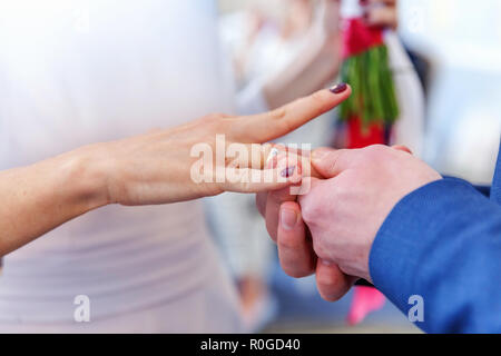 Mariée et le marié mariage mains avec les anneaux de mariage. Groom part mettre sur bague de mariage mariée doigt. Déclaration d'amour, au printemps. Carte de mariage d'accueil. Jour de mariage cérémonie moments détails Banque D'Images