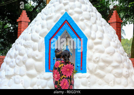 Une femme catholique prie devant la statue de Mère Marie Saint John's Church dans le Tumulia Gazipur, couverte de fleurs d'observer tous les jours des morts, Banque D'Images