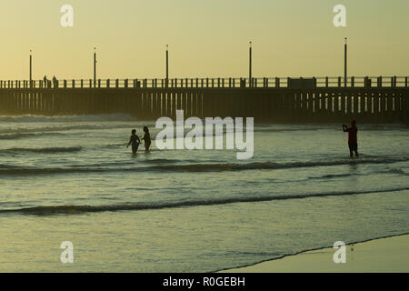 Durban, le KwaZulu-Natal, Afrique du Sud, seul mâle adulte de prendre photo de deux femmes debout dans l'eau tandis que sur le front de mer à Banque D'Images