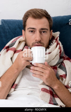 Portrait en gros plan d'un jeune homme de foulard avec tasse de thé looking at camera Banque D'Images