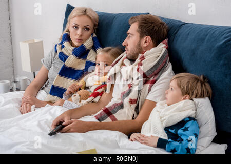 Les jeunes malades dans la famille de foulards en position couchée dans le lit Banque D'Images