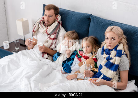 Sick young family sitting in bed Banque D'Images