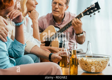 Cropped shot de vieux amis de boire une bière et jouer la guitare acoustique à la maison Banque D'Images
