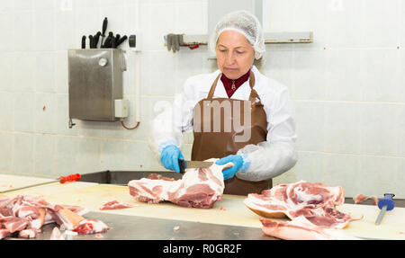 Portrait de femmes qualifiés worker cutting la viande crue dans l'usine de conditionnement des viandes Banque D'Images