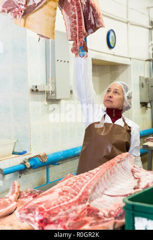 Portrait de femmes qualifiés worker cutting la viande crue dans l'usine de conditionnement des viandes Banque D'Images