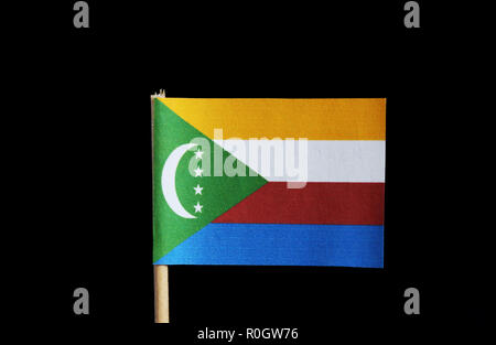 Un drapeau national des Comores sur cure-dent sur fond noir. Quatre bandes horizontales de jaune, blanc, rouge et bleu avec un chevron vert basé sur Banque D'Images