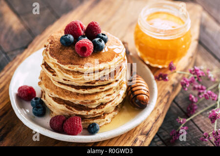 Crêpes à l'avoine framboises, bleuets et miel sur du conseil en bois Banque D'Images