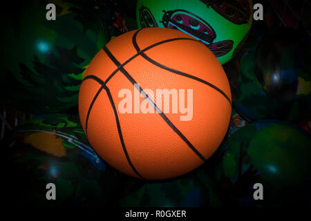 Basket Ball orange vif contre peint en vert avec des boules de vignette sombre Banque D'Images