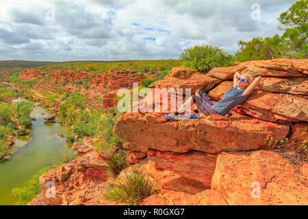 Femme blonde se reposant après l'escalade sur le rocher de grès rouge à Hawks Head lookout sur Murchison River dans le Parc National de Kalbarri, dans l'ouest de l'Australie. Meilleur de race blanche bénéficiant de l'Australie outback. Banque D'Images