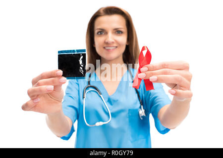 Smiling attractive doctor holding condom et ruban rouge isolé sur blanc, concept de la journée mondiale du sida Banque D'Images